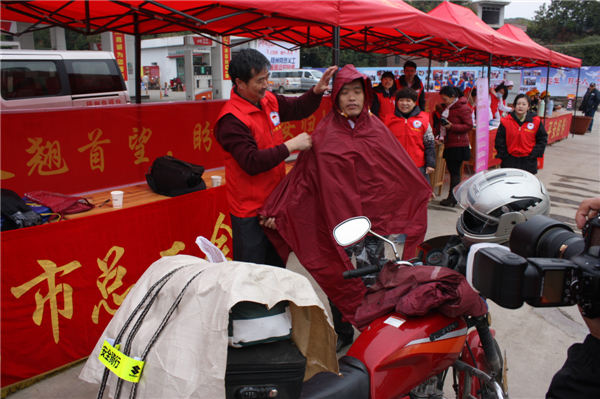 梧州市總工會的黨員義工們在市東出口春運服務站助力“摩托大軍”平安返鄉(xiāng)，幫助他們檢查車輛和行李，穿上雨衣。--黃賀峰攝.j